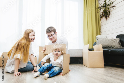 Family together happy young beautiful with a little baby moves with boxes to a new home