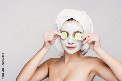 Beautiful girl with applied clay mask at white background