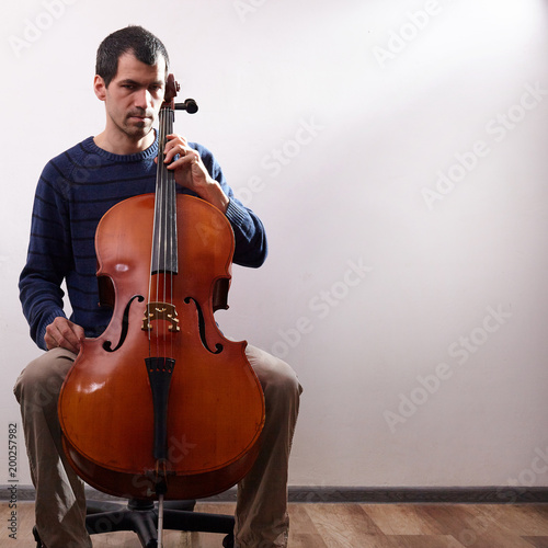Man with cello in room with wall