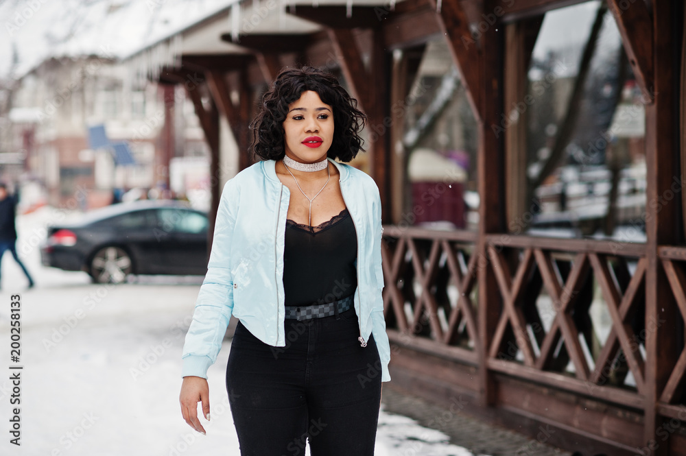 Stylish african american plus size model against wooden cafe at winter day.