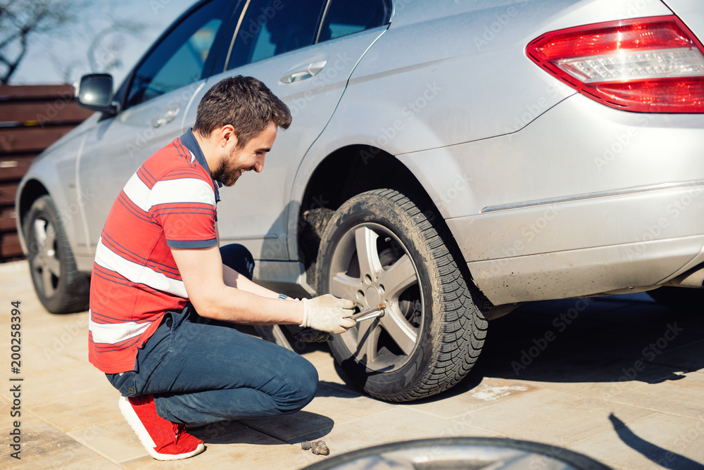 Automobile problems - man chaning tires, seasonal summer tires Automobile problems - man chaning tires, seasonal summer tires