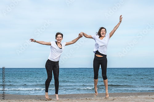 Two girls jumping on the beach