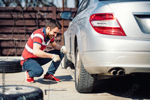 Portrait of young adult changing tires for season change