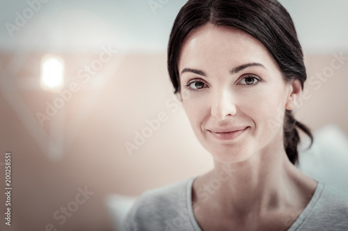 Be yourself. Pleasant cute confident woman spending time in the spacious room smiling and looking straight.
