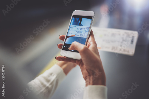 Closeup view of woman on transit platform using smartphone for make photo of train ticket while waiting rail train on metro station. photo
