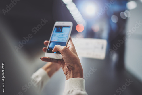 Closeup view of girl on transit platform using smartphone for make photo of train ticket while waiting rail train on metro station.