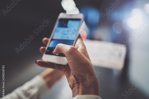 Closeup view of girl on transit platform using smartphone for make photo of train ticket while waiting rail train on metro station. photo