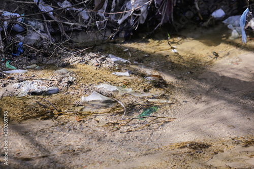 Fotografia Heavy polluted water stream with domestic garbage