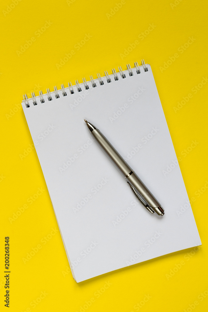 Notepad, pen, on a yellow background flat top view with copy space,layout,mocap Notepad, pen, on a yellow background flat top view with copy space,layout,mocap