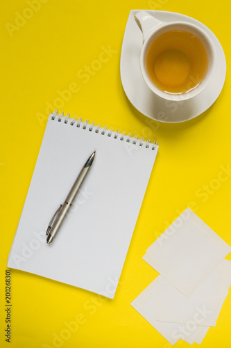 Notepad, pen, tea on a yellow background flat top view with copy space,layout,mocap