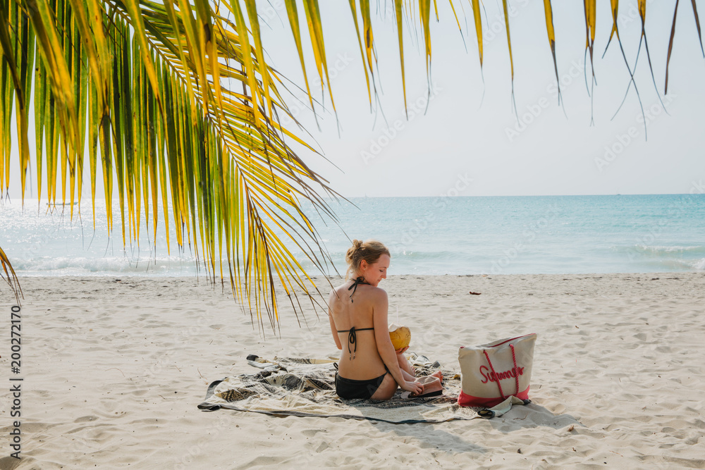 Eine junge Frau sitzt am Strand in der Karibik