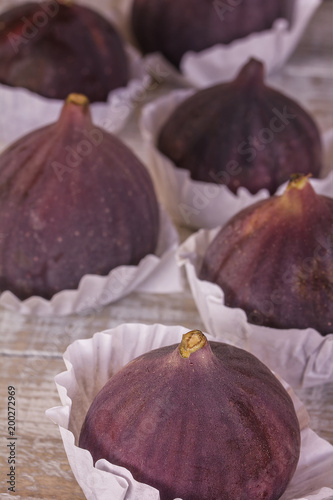 Figs fresh beautiful violet in paper shapes six pieces on a white wooden background, close-up