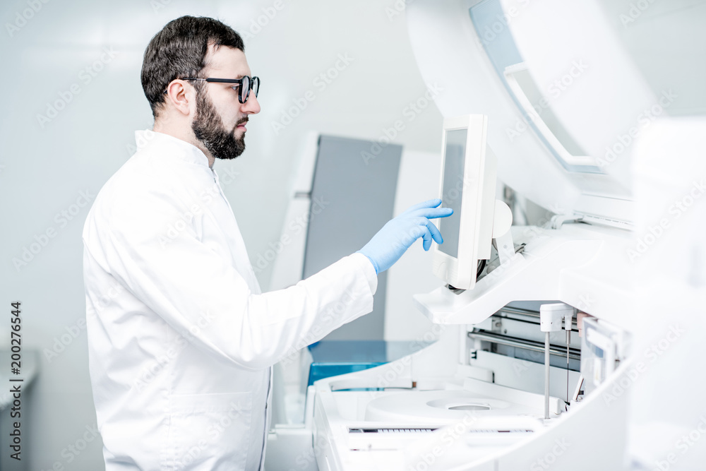 Laboratory assistant touching the screen of the medical analizer machine working in the laboratory Laboratory assistant touching the screen of the medical analizer machine working in the laboratory