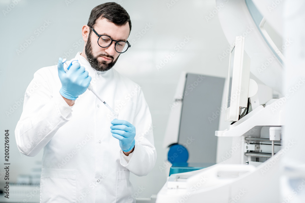 Laboratory assistant working with test tube near the medical analizer machine at the laboratory Laboratory assistant working with test tube near the medical analizer machine at the laboratory