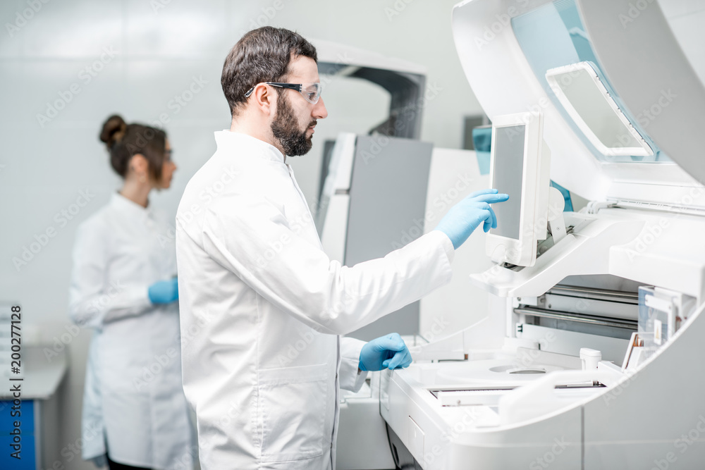 Laboratory assistants working with analizer Laboratory assistants working with analizer