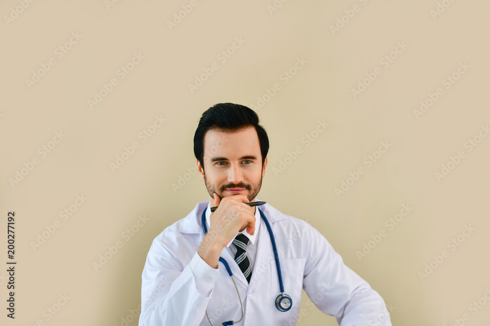 Smiling doctor posing in the office, he is wearing a stethoscope, medical staff on the hospital background Smiling doctor posing in the office, he is wearing a stethoscope, medical staff on the hospital background