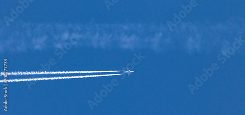 Flugzeug mit Kondensstreifen am blauen Himmel