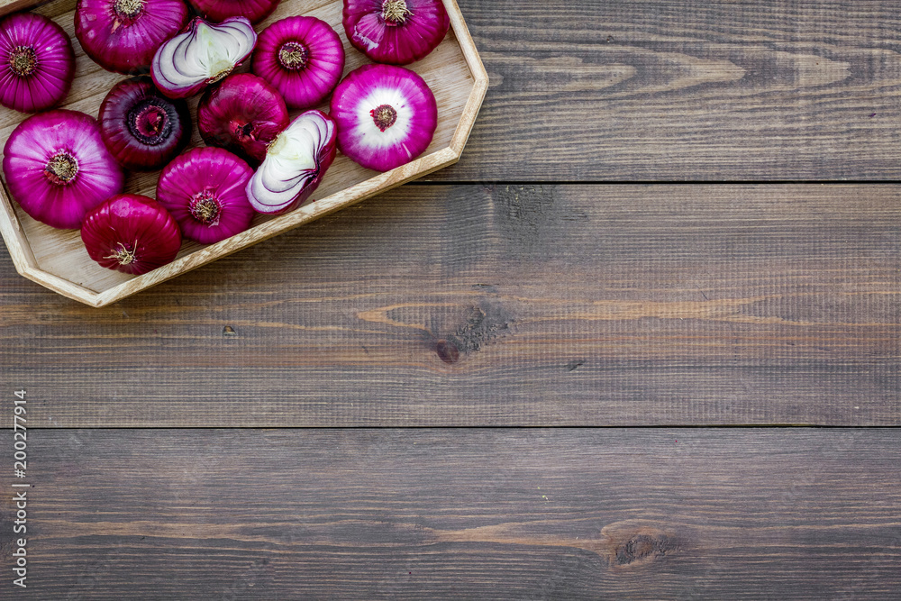 Red onion is healthy product. Onion bulbs in tray on dark wooden background top view copy space