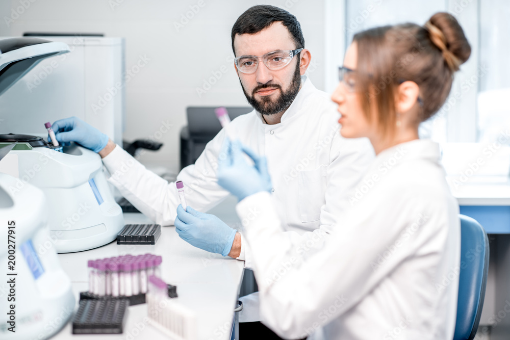 Laboratory assistants making analysis with test tubes and analyzer machines sitting at the modern laboratory Laboratory assistants making analysis with test tubes and analyzer machines sitting at the modern laboratory
