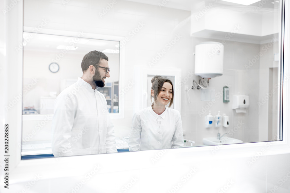 View through the glass on the two medics in uniform standing in the procedural office View through the glass on the two medics in uniform standing in the procedural office