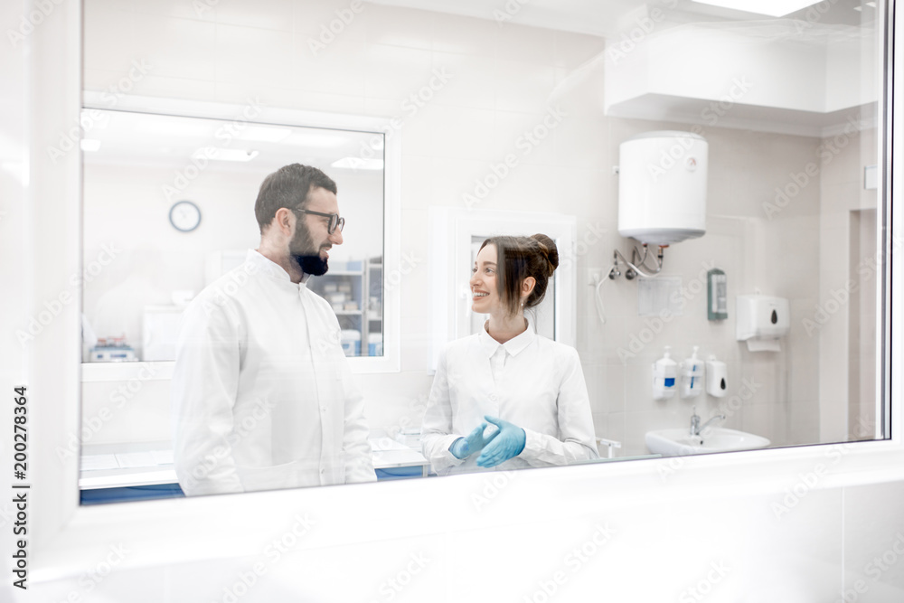 View through the glass on the two medics in uniform standing in the procedural office View through the glass on the two medics in uniform standing in the procedural office