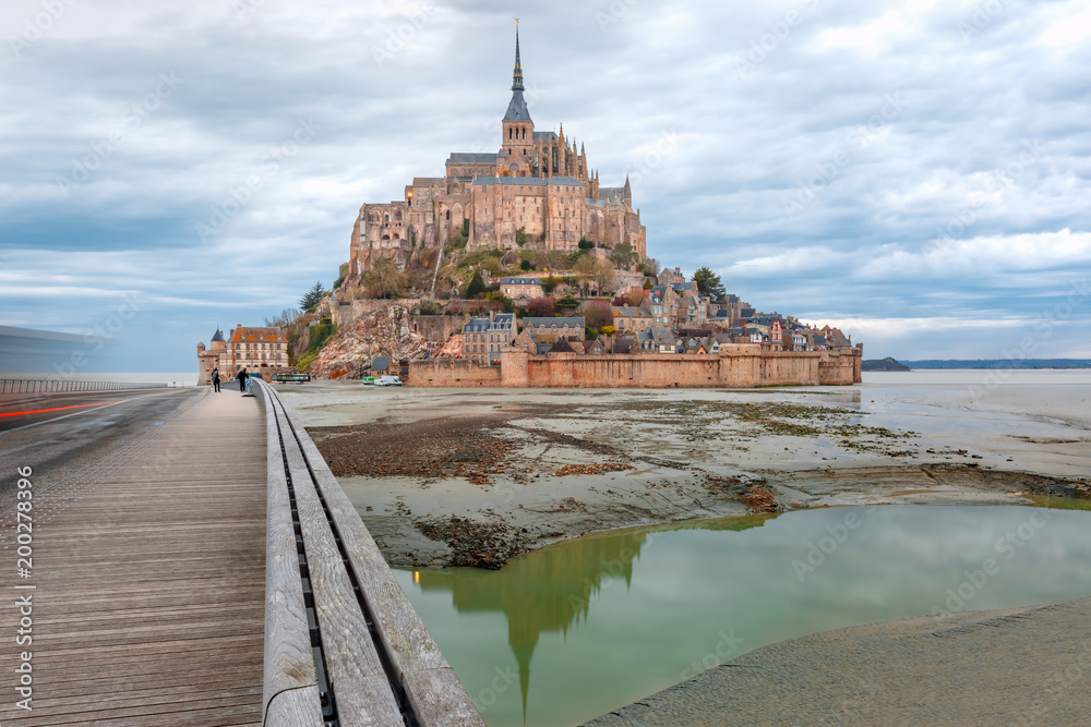 Beautiful famous Mont Saint Michel with bridge and reflection in the canal  at low tide in the cloudy morning, Normandy, France Stock-Foto | Adobe Stock