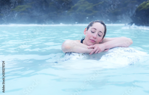 Woman resting on a rock in a hot spring 