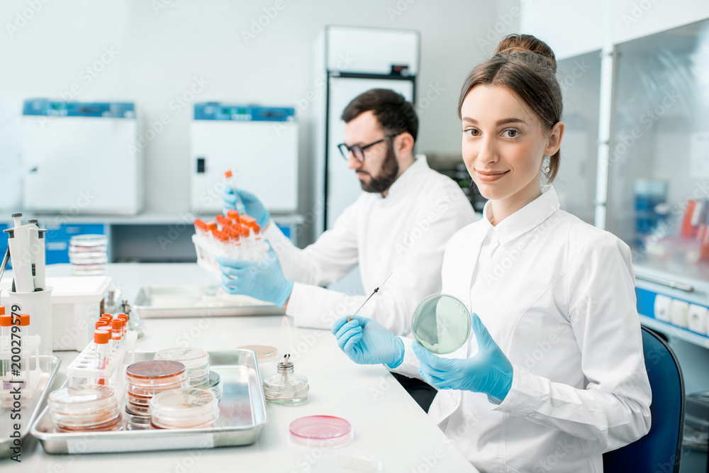 Couple of medics in uniform making bacteriological tests sitting in the modern laboratory Couple of medics in uniform making bacteriological tests sitting in the modern laboratory