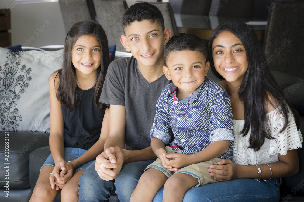 Smiling siblings in the living room. Two brothers and two sisters ...
