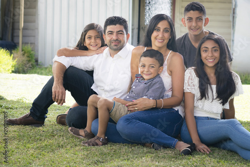 Happy family sitting in garden. Portrait of a smiling family outdoors, sitting together on green grass.