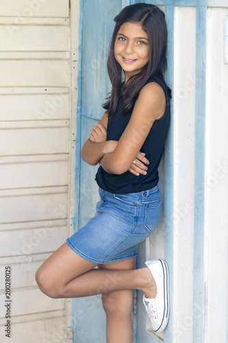 Portrait of a cute little girl in garden. Outdoor portrait of a smiling brunette girl, white wall in background. Free Download Portrait of a cute little girl in garden. Outdoor portrait of a smiling brunette girl, white wall in background. - GFXLoad