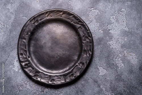 Empty black ceramic plate on grey background