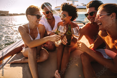 Multiracial friends toasting drinks on the yacht deck