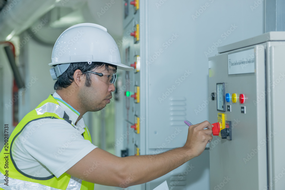 Asian electric engineer handsome man check load at Medium voltage switchgear,Bay control unit,Thailand people Asian electric engineer handsome man check load at Medium voltage switchgear,Bay control unit,Thailand people