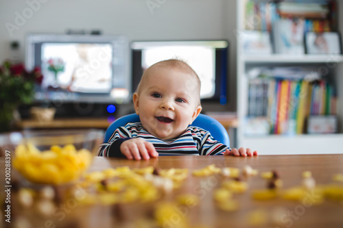 Cute little toddler boy eating cornflakes and smiling