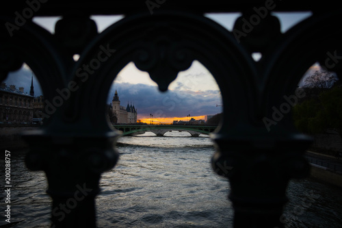 beautiful Parisian bridge against the backdrop of a magically setting sun seen in the early windy spring evening