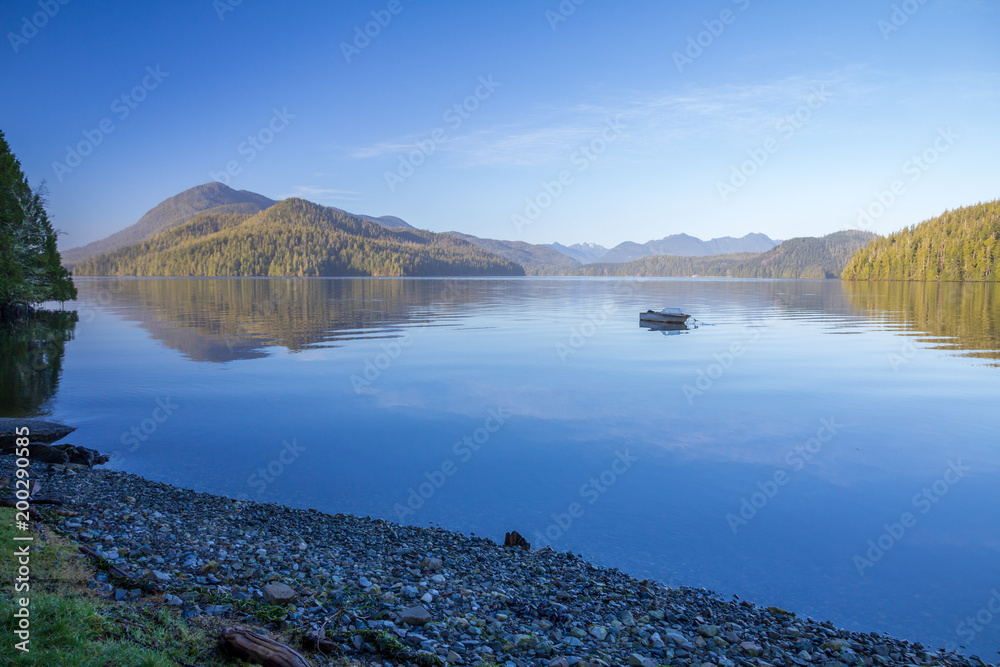 Calm waters of Grice Bay reflect Meares Island and boat.