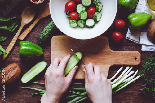hands cutting vegetables on wooden board photo