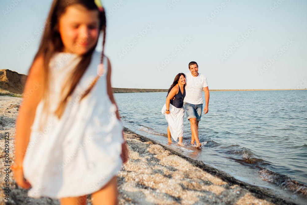 Young happy family walking along the seashore Young happy family walking along the seashore