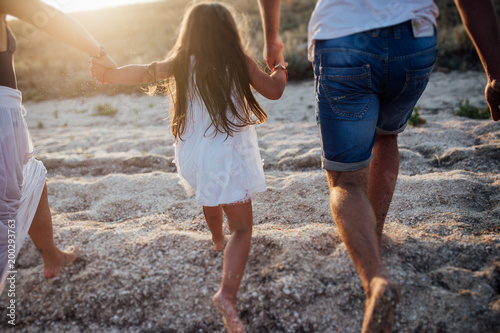 Young happy family walking along the seashore © Серегй Волков