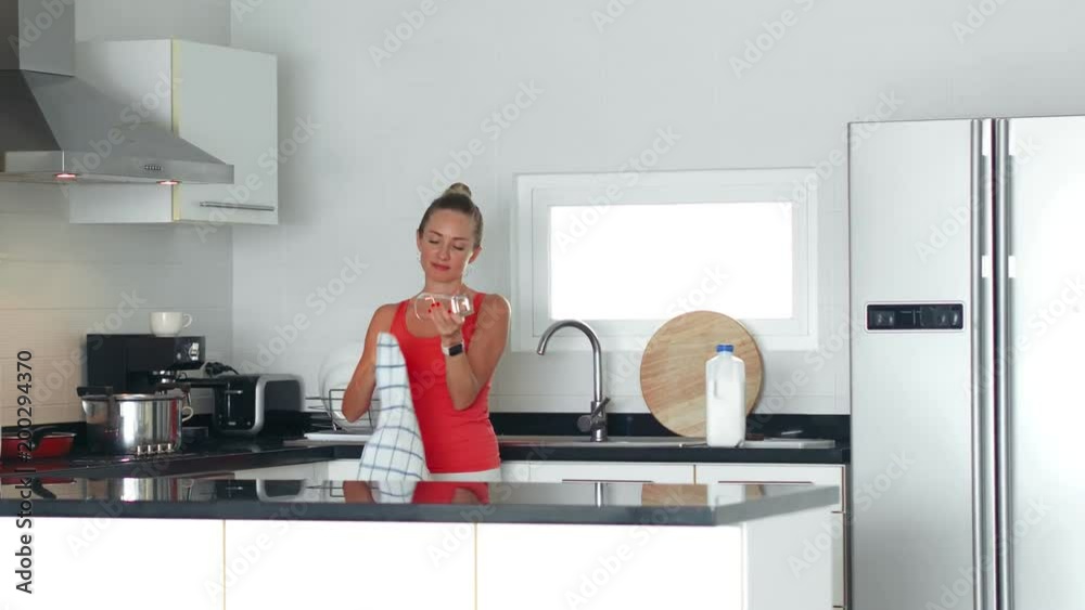 Beautiful housewife using kitchen towel for wiping glass during homemade. Adult woman doing house cleaning on cozy kitchen in apartment Beautiful housewife using kitchen towel for wiping glass during homemade. Adult woman doing house cleaning on cozy kitchen in apartment