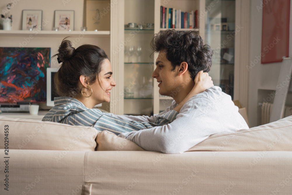 Cheerful young couple sitting on couch Cheerful young couple sitting on couch