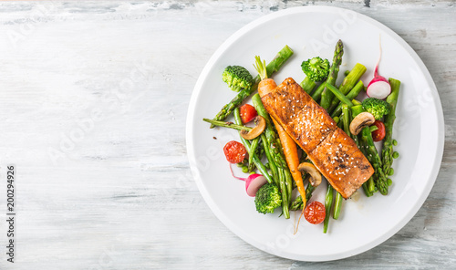 Photo Roasted salmon steak with asparagos broccoli carrot tomatoes radish green beans and peas
