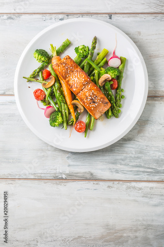 Roasted salmon steak with asparagos broccoli carrot tomatoes radish green beans and peas. Fish meal with fresh vegetable photo