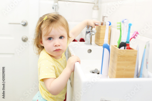 Cute little girl washing hands in bathroom