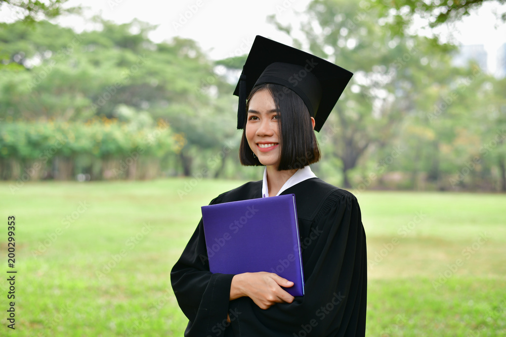 Graduation Concept. Graduated students on graduation day. Asian students are smiling happily on the graduation day. Students wear graduation gowns in the garden Graduation Concept. Graduated students on graduation day. Asian students are smiling happily on the graduation day. Students wear graduation gowns in the garden