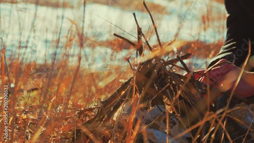 A man collects a fire from a fire in the autumn forest. Close up. photo