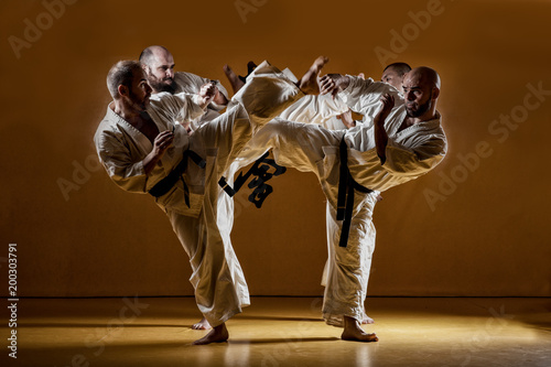 Four karate men fighting in a indoor dojo. photo