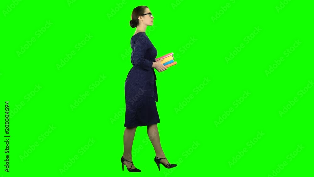 Student goes to school with books in her hands. Green screen. Side view Student goes to school with books in her hands. Green screen. Side view