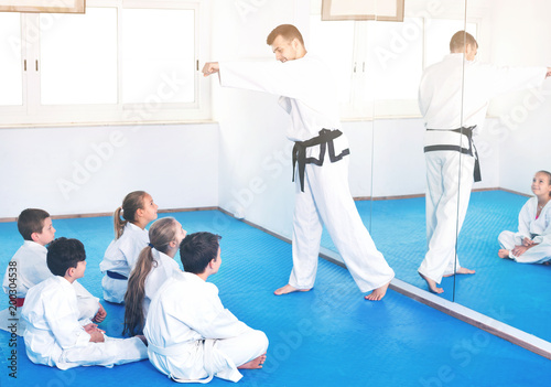Coach showing new martial moves to children in karate class